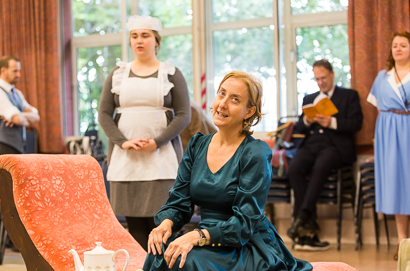 In our rehearsal hall society member Asun Del Valle sits elegantly on a chaise lounge while another member in the background studies his script